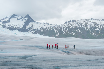 Hikers in colorful coats walking on a glacier surrounded by mountains