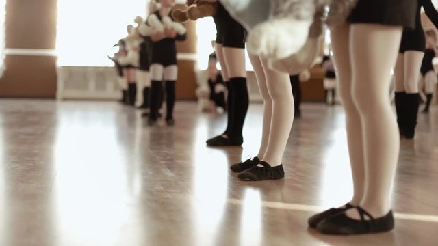 Little girls for a dance class. Close up. Black swimsuit and white tights. Slow motion