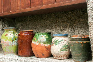 Various ceramic pots next to each other in a row in stone niche on house garden wall