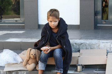 Poor little boy with bread on city street