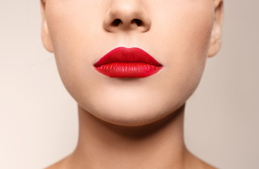 Beautiful young woman with red lips on color background, closeup