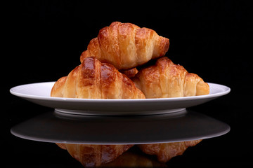 Tasty croissants with plate on black backgound