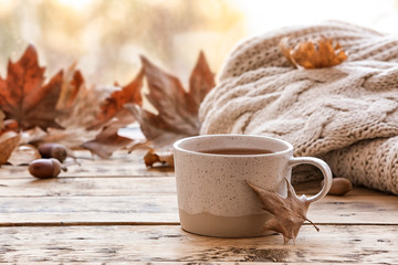 Composition with cup of hot cozy drink and autumn leaves on windowsill. Space for text