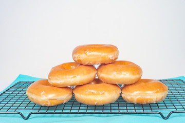 Close up of six stacked glazed doughnuts isolated on white with copy space