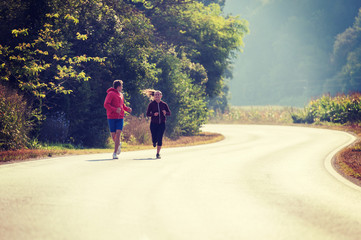 young couple jogging along a country road