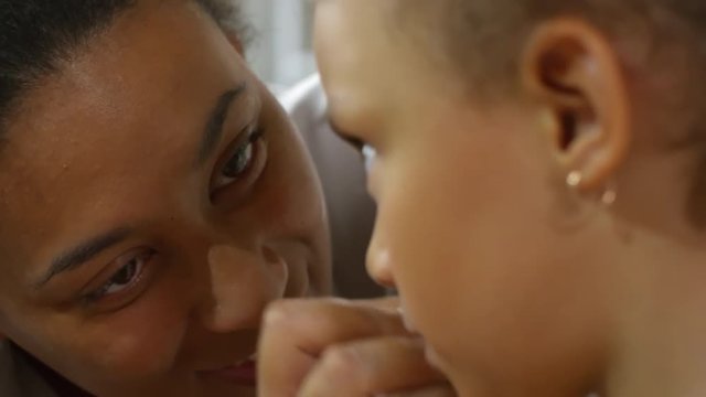 Close up shot of loving black woman removing makeup from little daughter’s face and kissing her