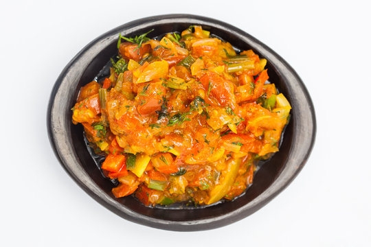 Traditional Colombian sauce called hogao served in a black ceramic dish isolated on white background