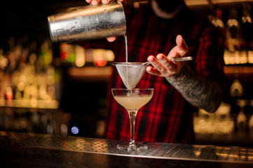 Bartender pourring a Daiquiri cocktail from the shaker through the sieve