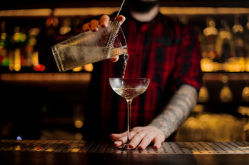 Bartender pourring a Twinkle achoholic cocktail drink from the measuring cup