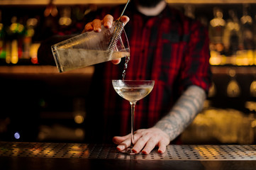 Bartender pourring a Twinkle achoholic cocktail from the measuring cup