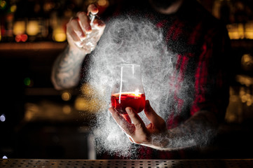 Bartender spraying on the Sazerac cocktail with orange zest © fesenko