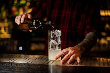 Bartender pourring a achohol from the bottle making cocktail