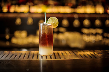 Dark Stormy cocktail decorated with lime slice on the bar counter