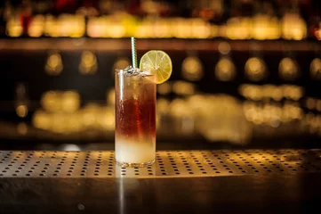 Photo sur Aluminium Cocktail Cocktail orageux sombre décoré de tranche de citron vert sur le comptoir du bar