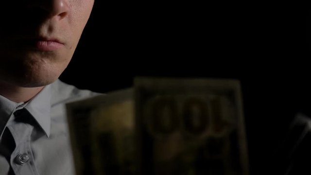 A man in the dark counting dollars. The man counts the dollars. Money in men's hands. Unexpected win. The fee for the work done.He shakes with money. Close up. Slow motion. 4K
