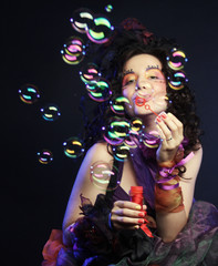 fashion model with creative make-up blowing soap bubbles. 