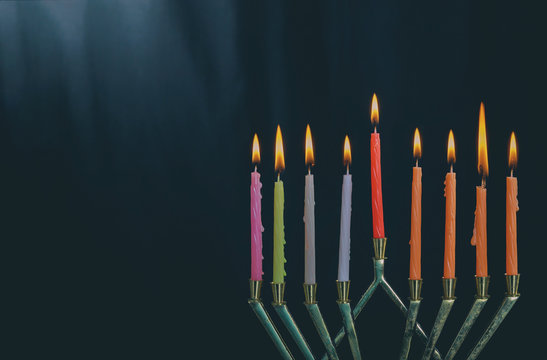 The lit of hanukkah candles in menorah on blue background