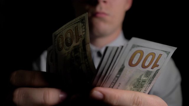 A man in the dark counting dollars. The man counts the dollars. Money in men's hands. Unexpected win. The fee for the work done.He shakes with money. Close up. Slow motion. 4K