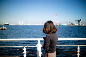 A fashionable and slim young lady looking out to sea.