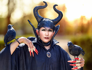 Attractive woman wearing a Halloween costume of a wizard with fake birds and fake fingernails