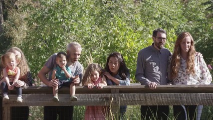 Group of people standing next to fence while at a zoo looking at an exhibit.
