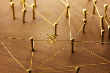Linking entities. Dispute or conflict, or Bottleneck between two entities. Network, networking, social media, internet communication abstract. Web of gold wires on rustic wood. - obrazy, fototapety, plakaty