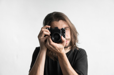 Handsome young bearded man with a long hair and in a black shirt holding vintage old-fashioned film...