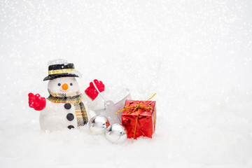 Snowman with gift box is standing in snowfall, Merry Christmas and happy New Year concept
