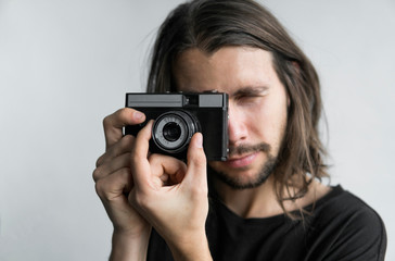 Handsome young bearded man with a long hair and in a black shirt holding vintage old-fashioned film...