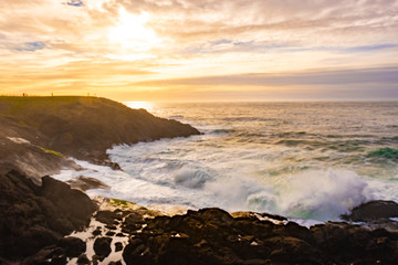 Ocean waves crashing onto the rocks in the sunset