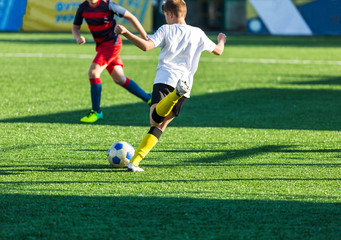 football teams - boys in red, blue, white sportswear play soccer on the green field. boys dribbling. dribbling skills. Team game, training, active lifestyle, hobby, sport for kids concept