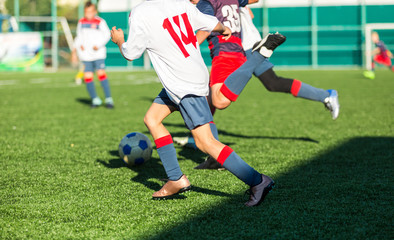 football teams - boys in red, blue, white sportswear play soccer on the green field. boys dribbling. dribbling skills. Team game, training, active lifestyle, hobby, sport for kids concept