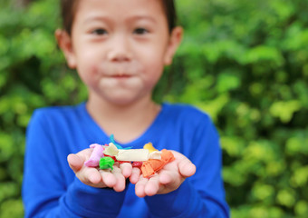 Close-up little Asian child girl holding some thai sugar and fruit toffee with colorful paper wrapped in her hands.