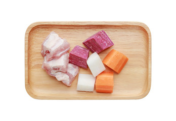 Ingredients for boiling soup (chopped carrot, radish, pork bone and purple potato) in wooden tray isolated on white background.
