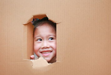 Happy Asian kid girl looking up from hole on cardboard with copy space.