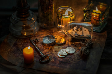 Fototapeta na wymiar Old coins, key, burning candles and compass on vintage map