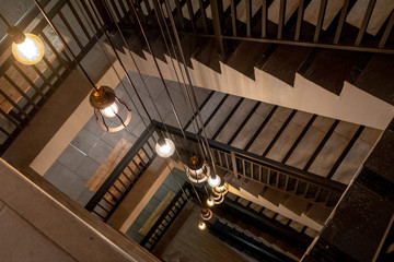 Staircase with Spiral Staircase build step by cement and vintage chandelier light on top floor.