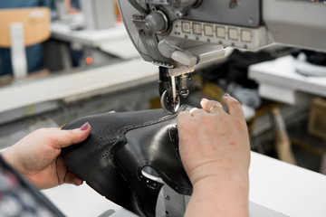 Sewing machine in a leather workshop in action with hands working on a leather details for shoes....