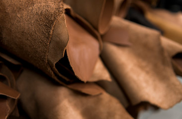 Different pieces of leather in a rolls. The pieces of the colored leathers. Rolls of natural brown red leather. Raw materials for manufacture of bags, shoes, clothing and accessories. © Volodymyr_sh