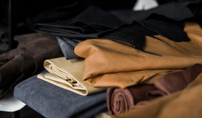 Different pieces of leather in a rolls. The pieces of the colored leathers. Rolls of natural brown red leather. Raw materials for manufacture of bags, shoes, clothing and accessories.