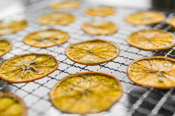 Candied orange slices on grid for drying. Dried fruits which can be used as a decoration to the meal or cocktails. Healthy vegetarian food rich on a vitamins and microelements.