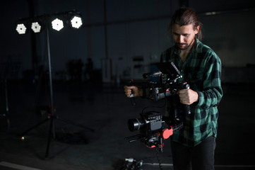 Professional videographer holding camera on 3-axis gimbal. Videographer using steadicam. Pro...