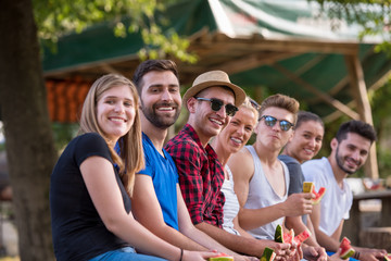 friends enjoying watermelon while sitting on the wooden bridge