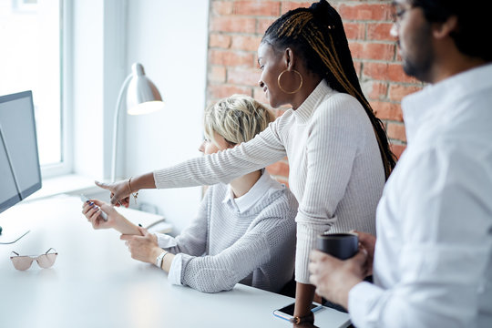 office workers studing together. afro girl pointing at the screen while watching the vebinar