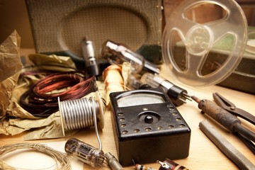 Vintage electronics. Vintage test meter and soldering equipment etc. Desk top of a retro 1960s - 1970s electrician, under incandescent light .