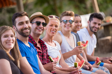 friends enjoying watermelon while sitting on the wooden bridge