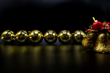 Golden Christmas baubles and bells with guitar on black background.