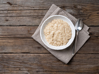Large bowl of tasty and healthy oatmeal for Breakfast, morning meal. Top view, close up, wooden rustic table