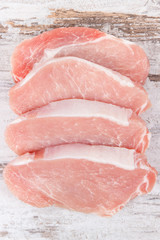 Slices of fresh loin for cooking on rustic board