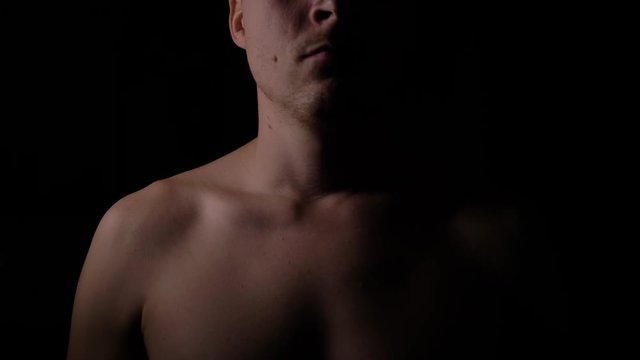 Naked upper body of a man. A man posing in the Studio in the dark.
